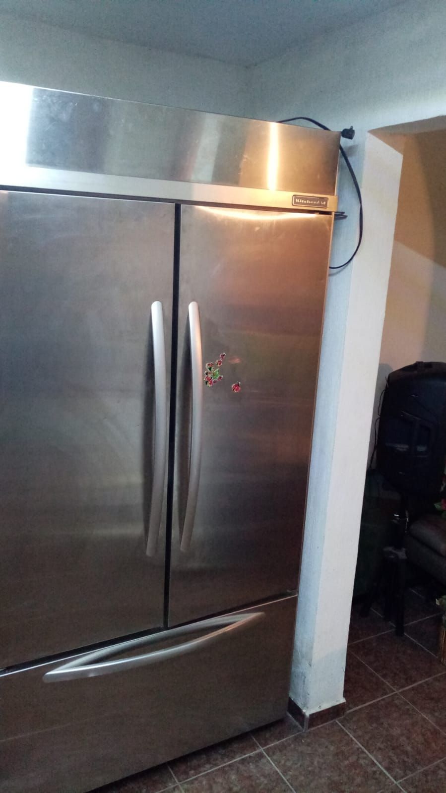 Un refrigerador de acero inoxidable está sentado junto a una pared en una cocina.