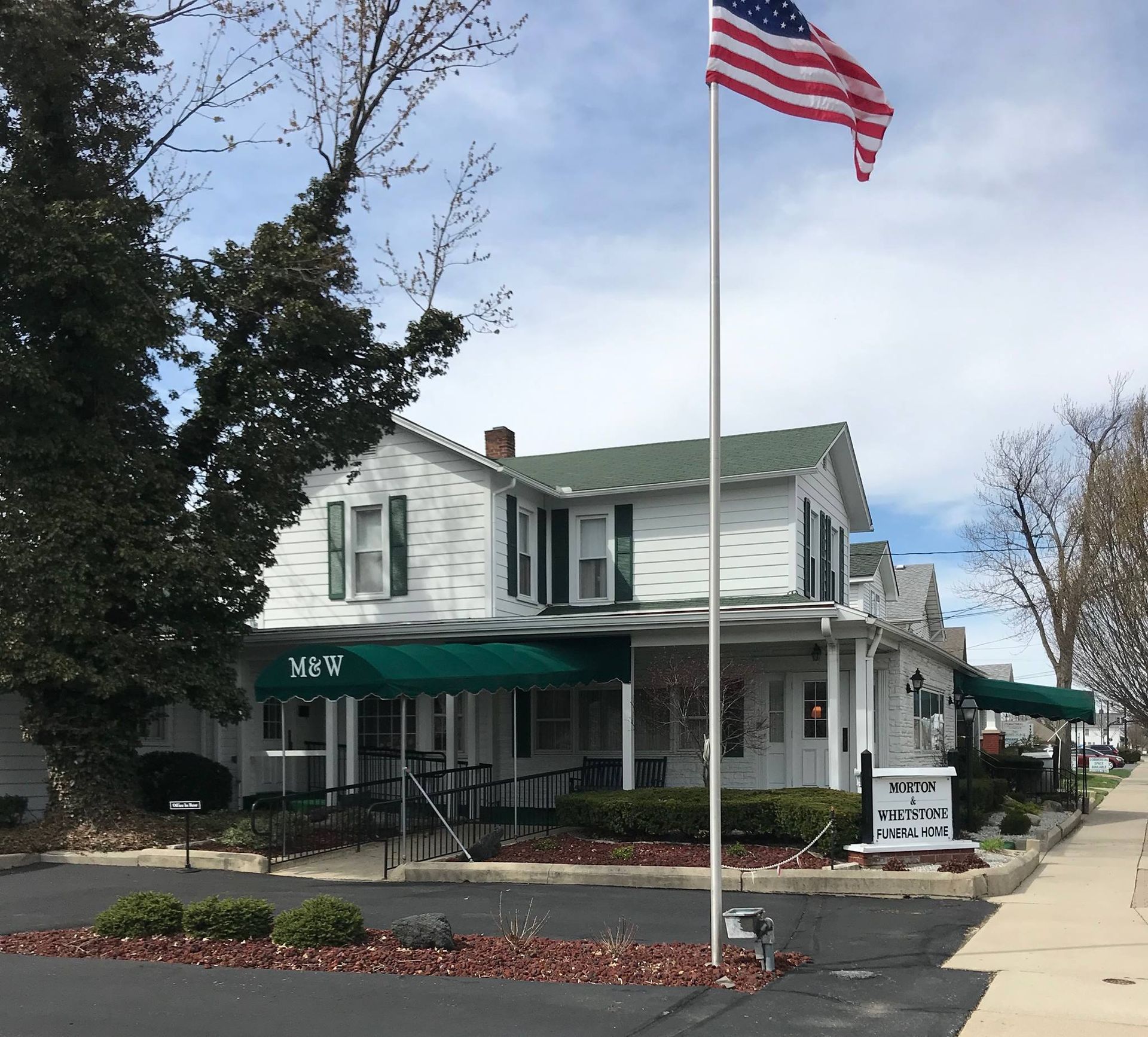 A large white house with a flag flying in front of it.