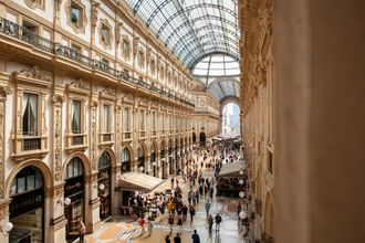 A high-angle view of the bustling Galleria Vittorio Emanuele II in Milan, featuring an ornate glass ceiling and shops.
