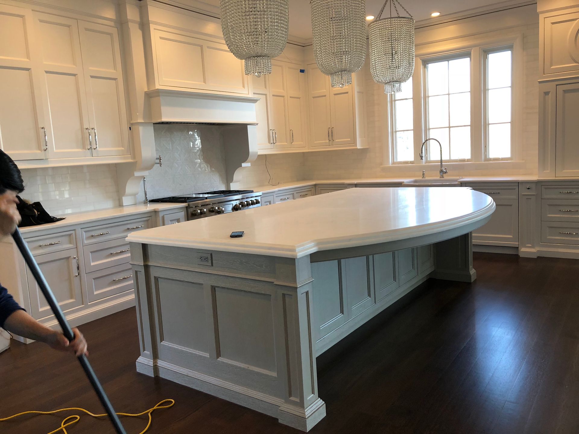 Person wearing purple gloves sprays and wipes a round mirror clean with a pink cloth.