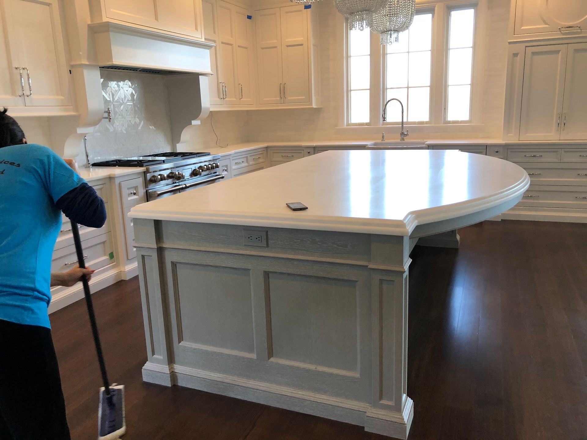 Hands in orange gloves cleaning a bathroom sink with spray bottle and cloth.