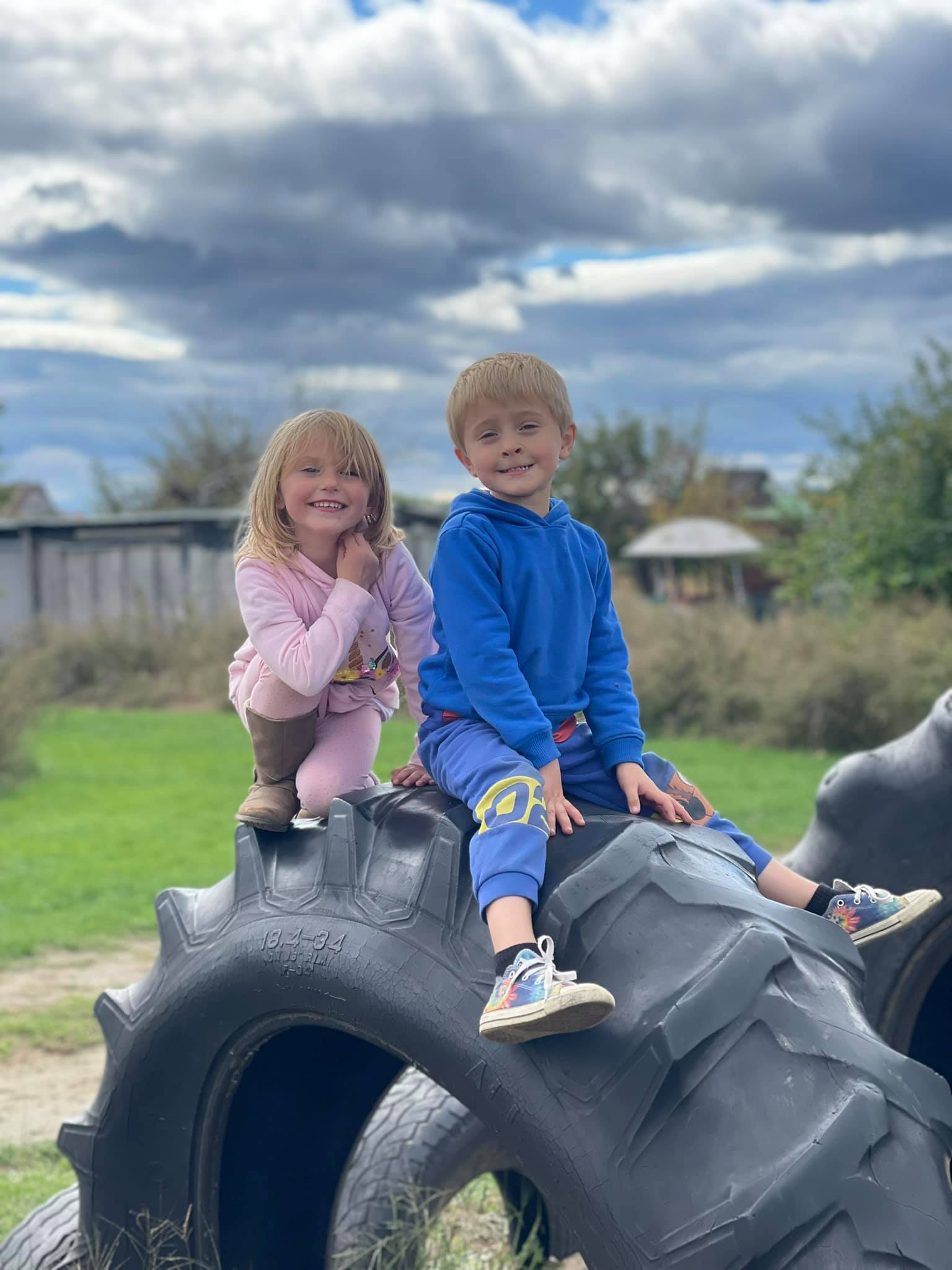 children sitting big truck wheel
