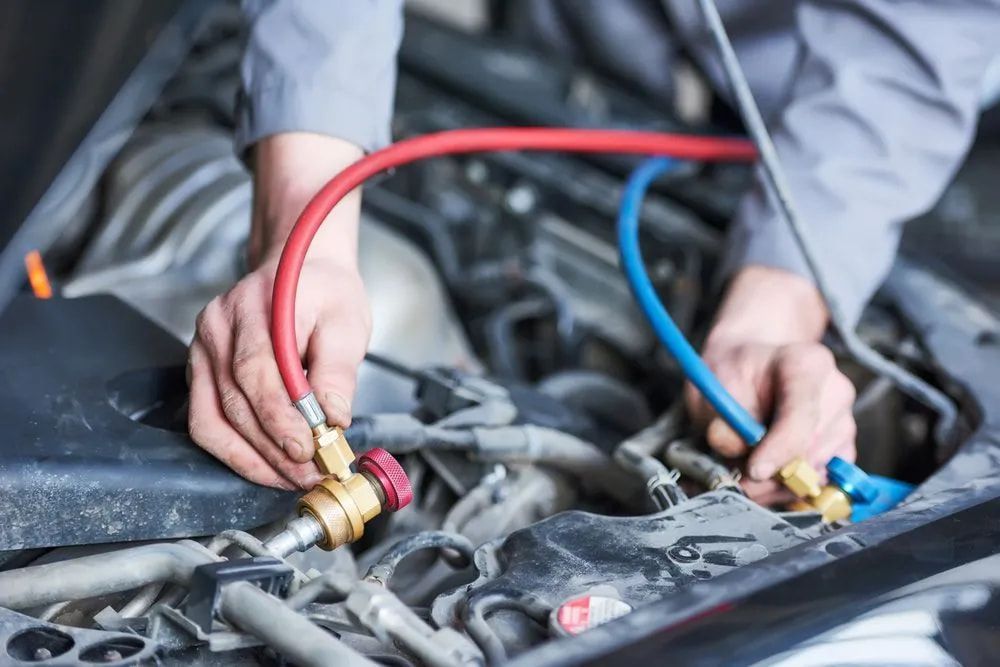 Mechanic Attaching Hoses to a Car Engine, Using Red and Blue Hoses — Cool Cars NT in Anula, NT