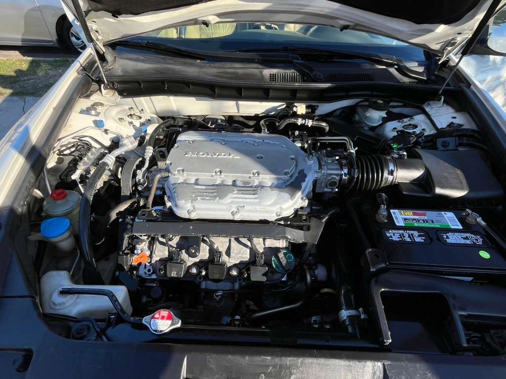 Car engine bay with hood open, showing a silver engine and battery compartment.