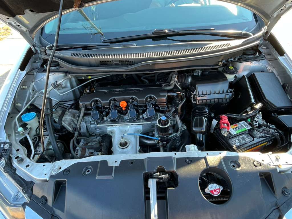 Open car hood showing the engine bay and battery compartment
