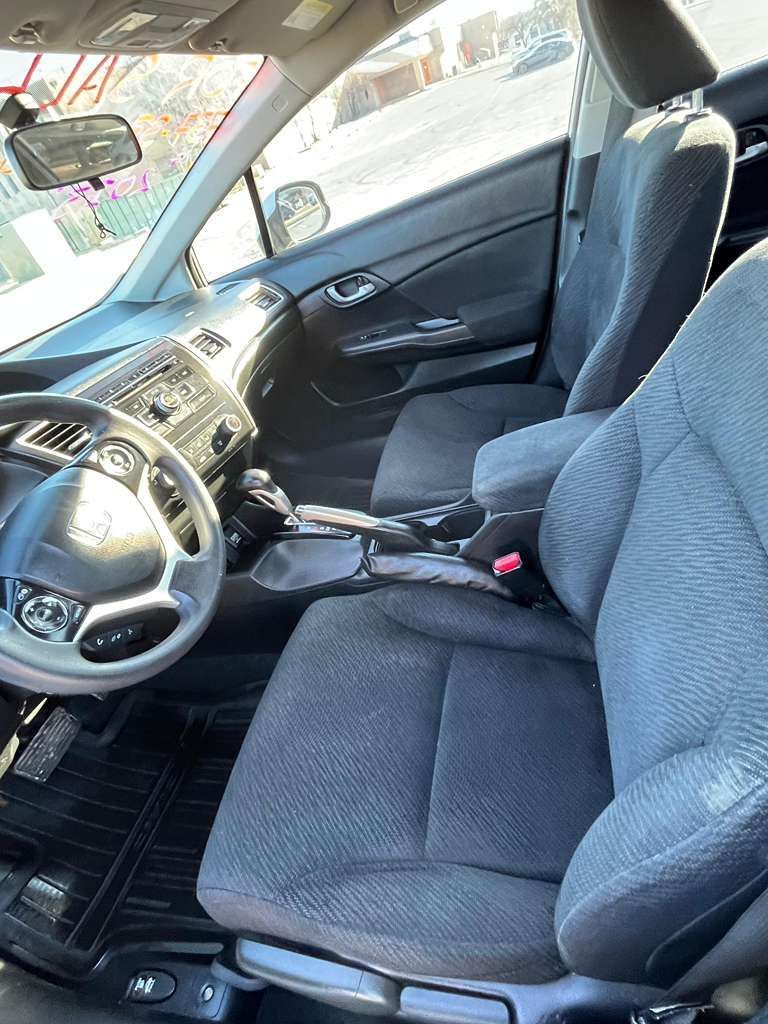 Car interior with gray cloth seats, steering wheel, and center console, viewed from the driver’s side