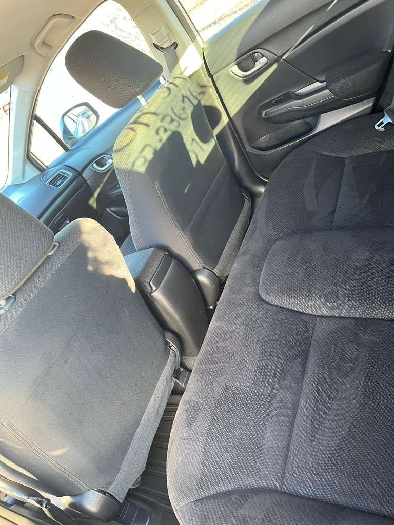 Car interior with black cloth seats and a green patterned seat cover in the back seat.