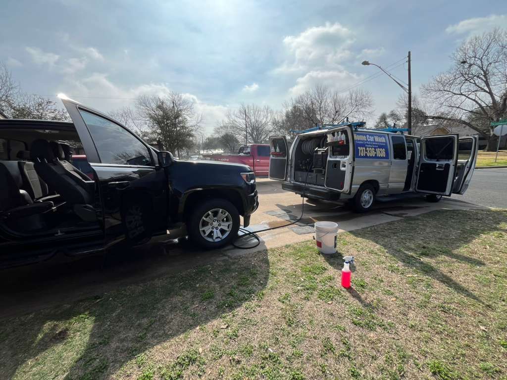 Black and silver vans parked on grass at an outdoor event under a cloudy sky