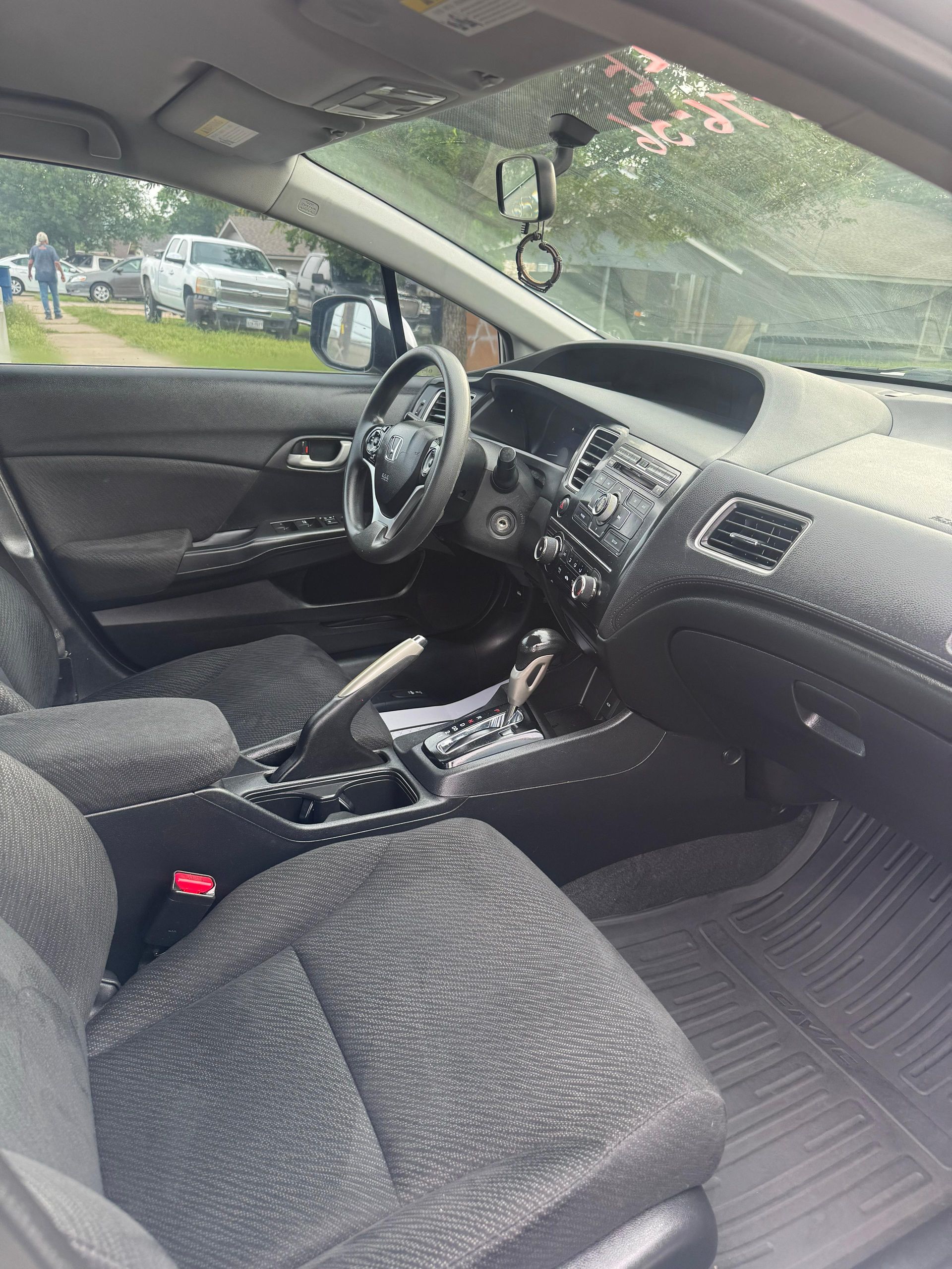 Car interior with dark fabric seats, steering wheel, dashboard, and center console visible