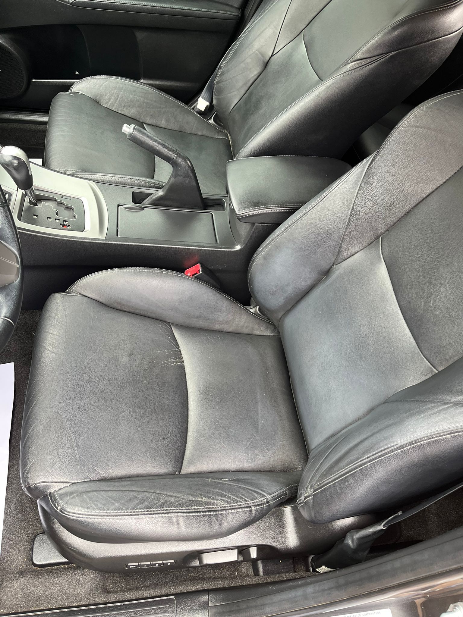 Black leather car interior with front seats and center console visible