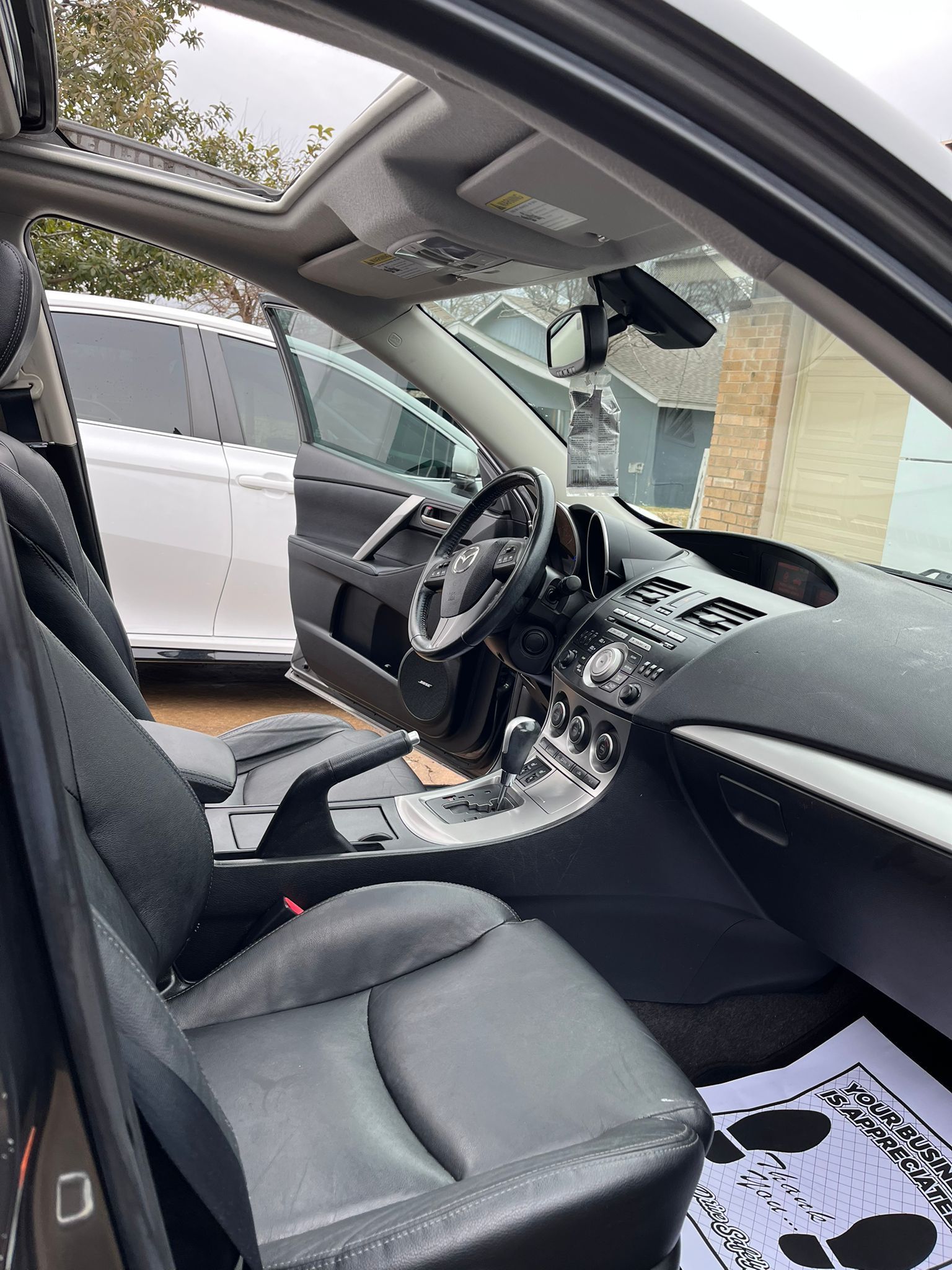 Car interior with open door, black seats, center console, and steering wheel visible from the passenger side.