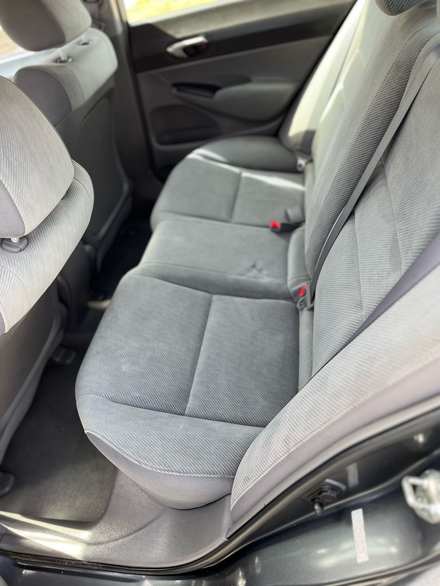 Gray car back seat with patterned upholstery and seatbelts in the interior