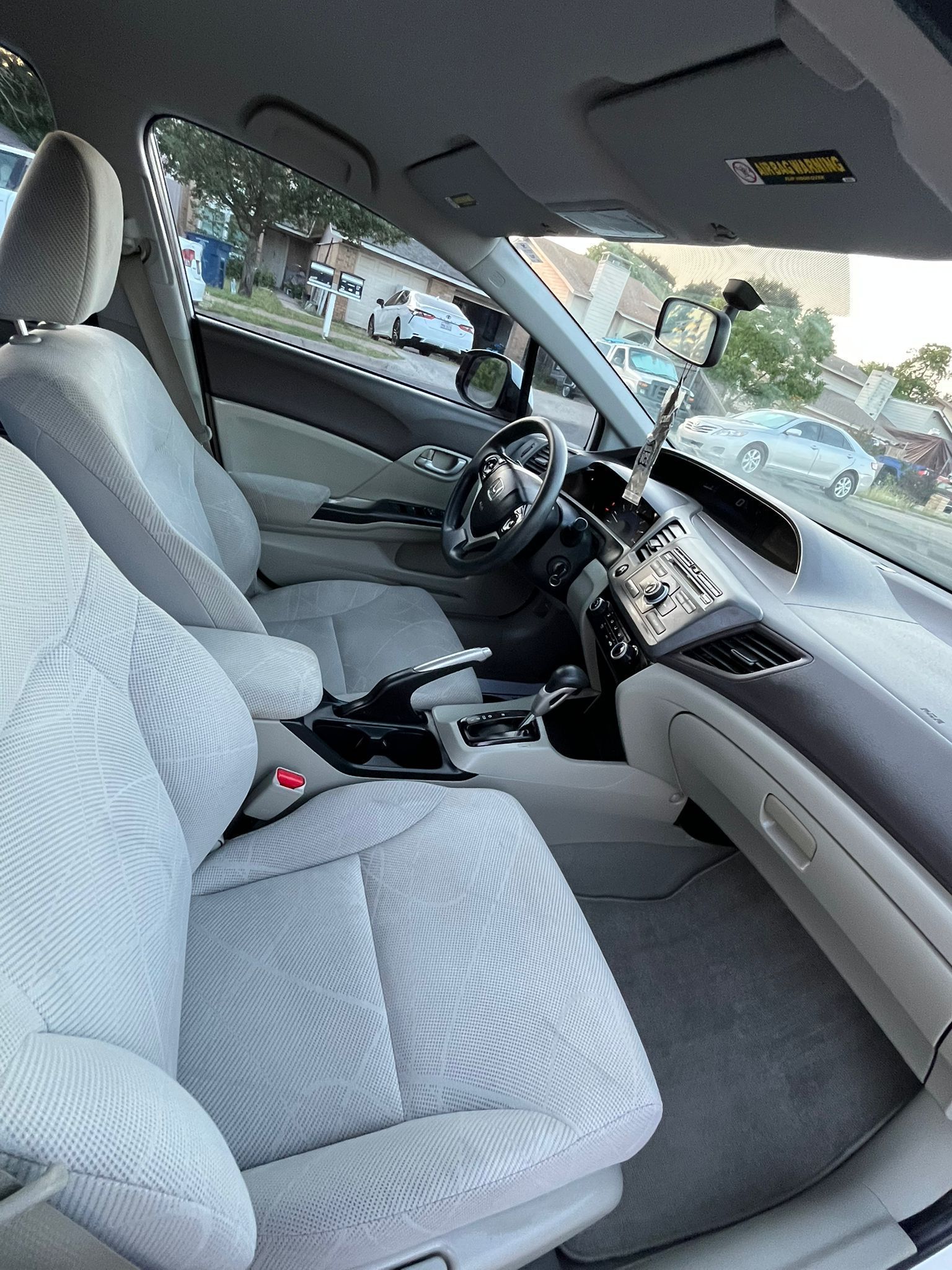 Car interior with gray seats and steering wheel, viewed from the passenger side with the door open