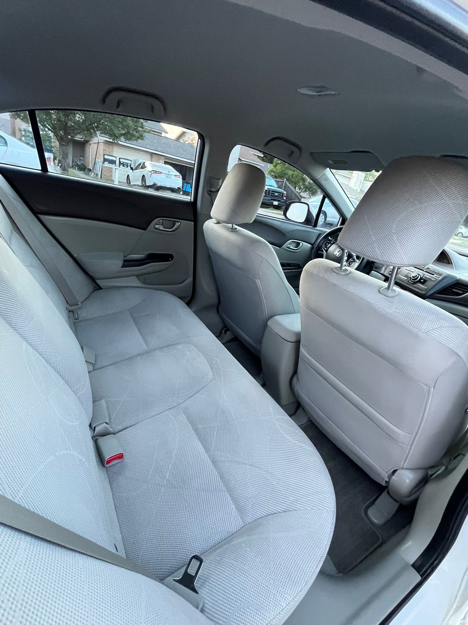 Car interior with light gray patterned seats, viewed from the back seat toward the front and side window.
