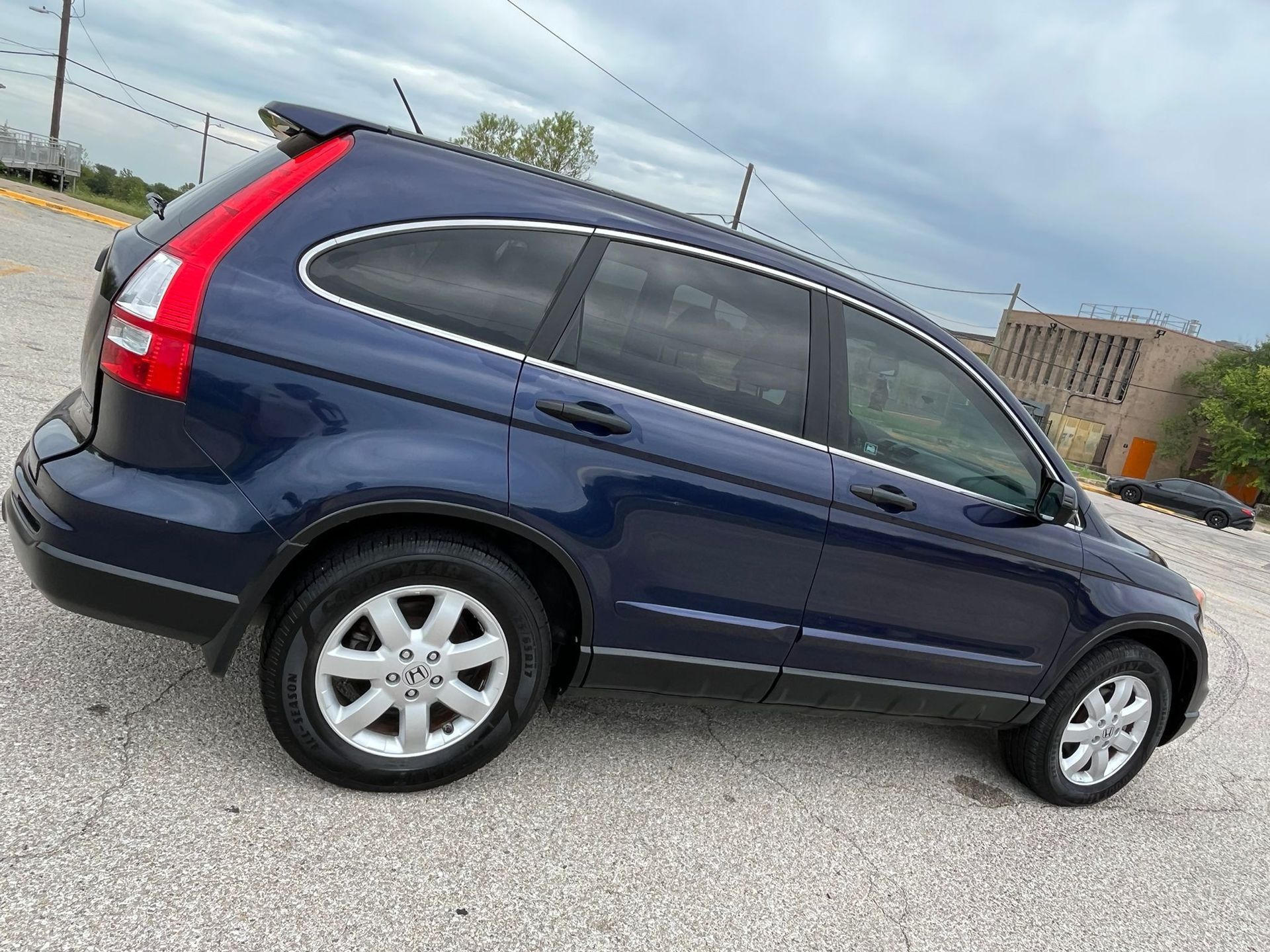 Blue SUV parked on a gravel lot under a cloudy sky