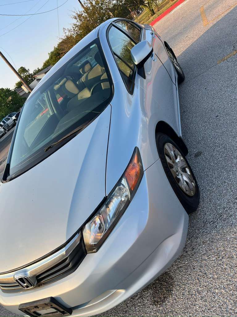 Silver Honda sedan parked at an angle on a roadside under daylight.