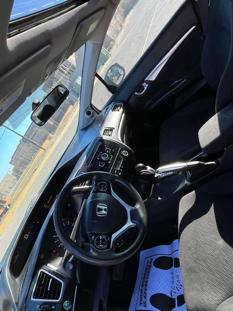 Interior of a car with steering wheel, dashboard, and front passenger seat, viewed from the driver’s side.