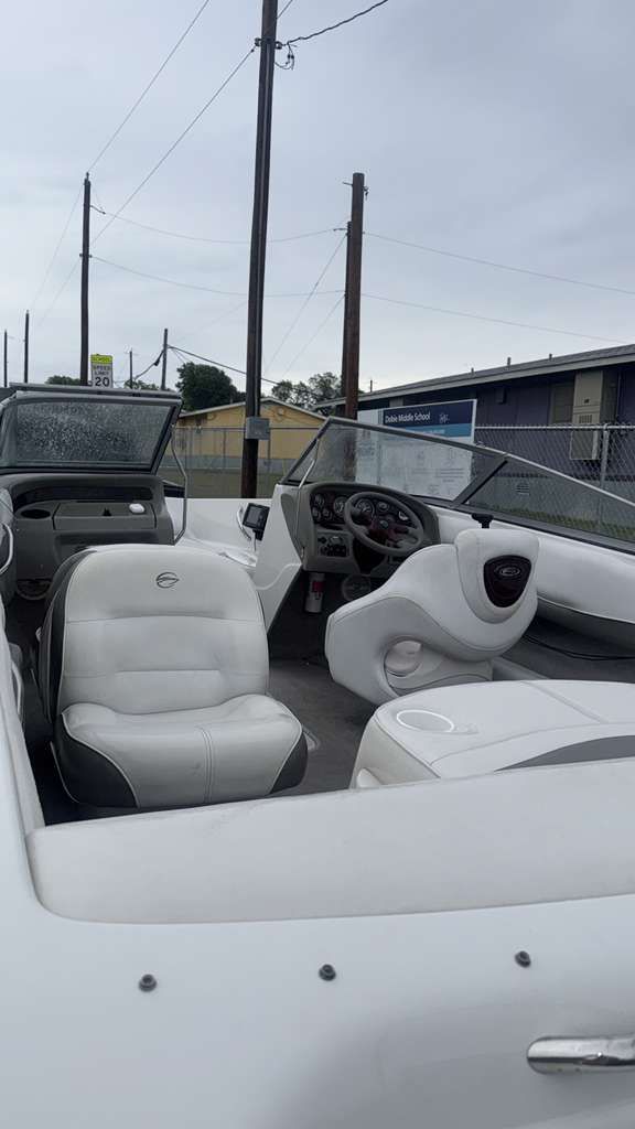 White convertible boat interior with gray seats parked near docks under cloudy sky