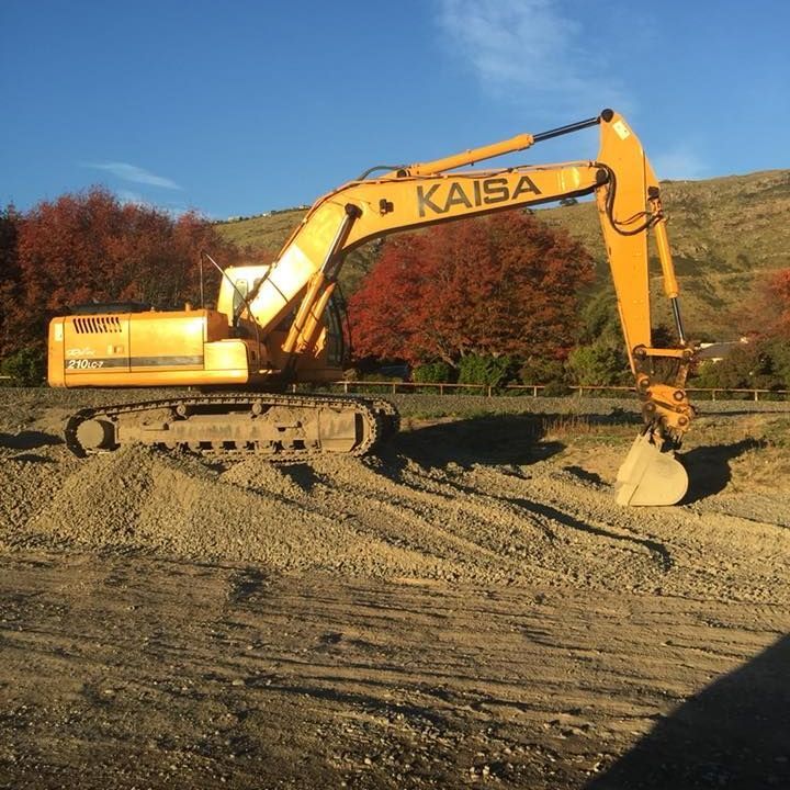 A yellow excavator is digging a hole in front of a building under construction. A yellow excavator is digging a hole in front of a building under construction.