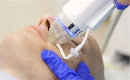 Gloved hand using a clear facial treatment device on a person’s chin
