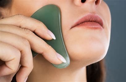 Person using a green facial roller on their cheek