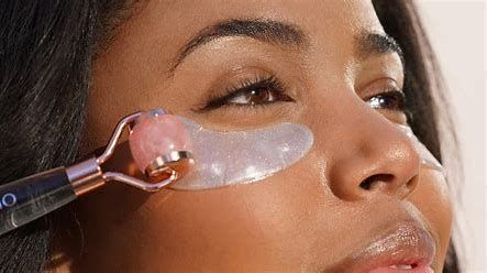 Close-up of a face with a rose quartz roller massaging the cheek under the eye.