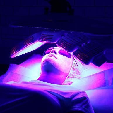 Person under purple UV light wearing a face mask during a cosmetic treatment