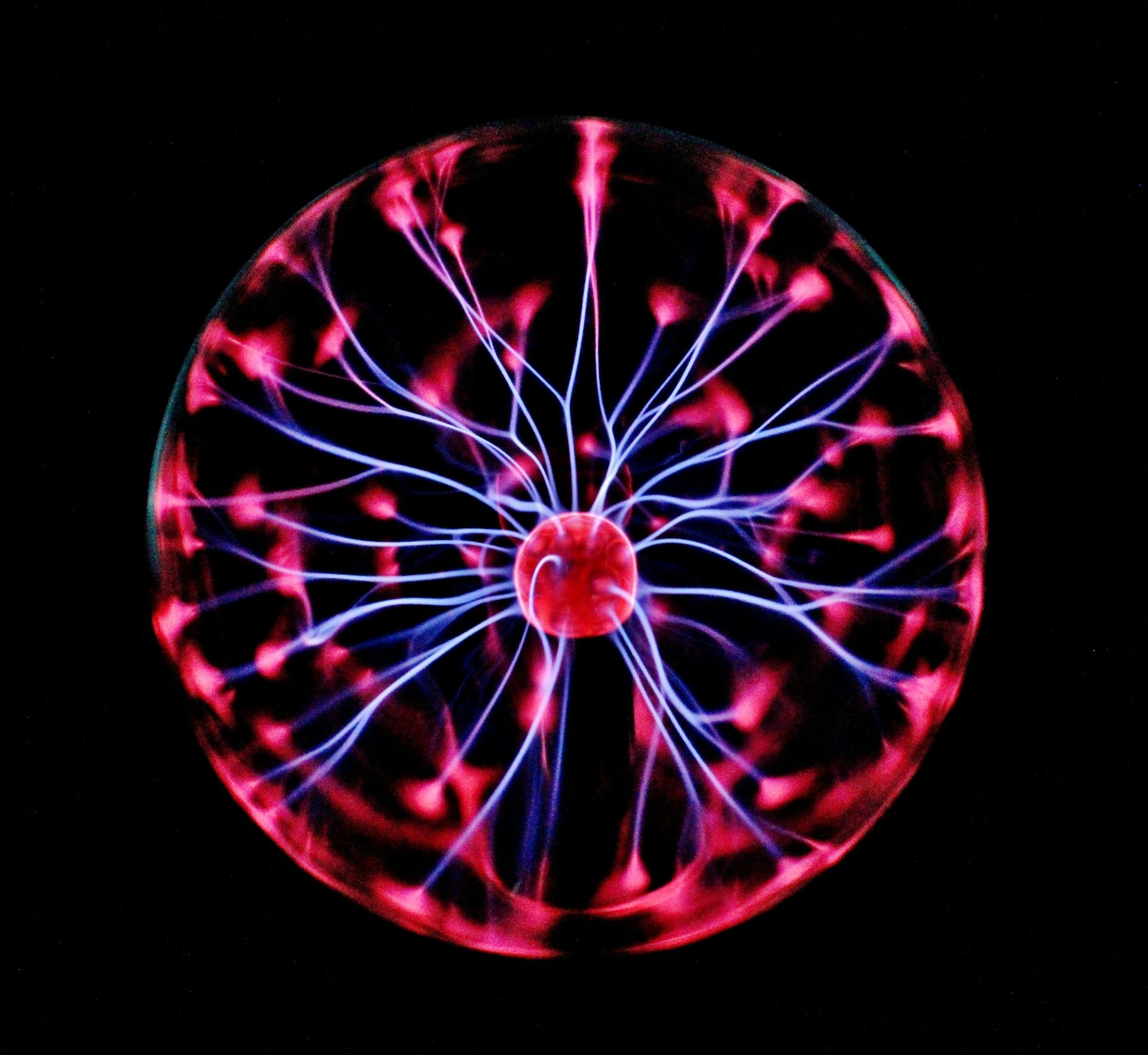 Glowing plasma globe with pink and blue электрic filaments on a black background