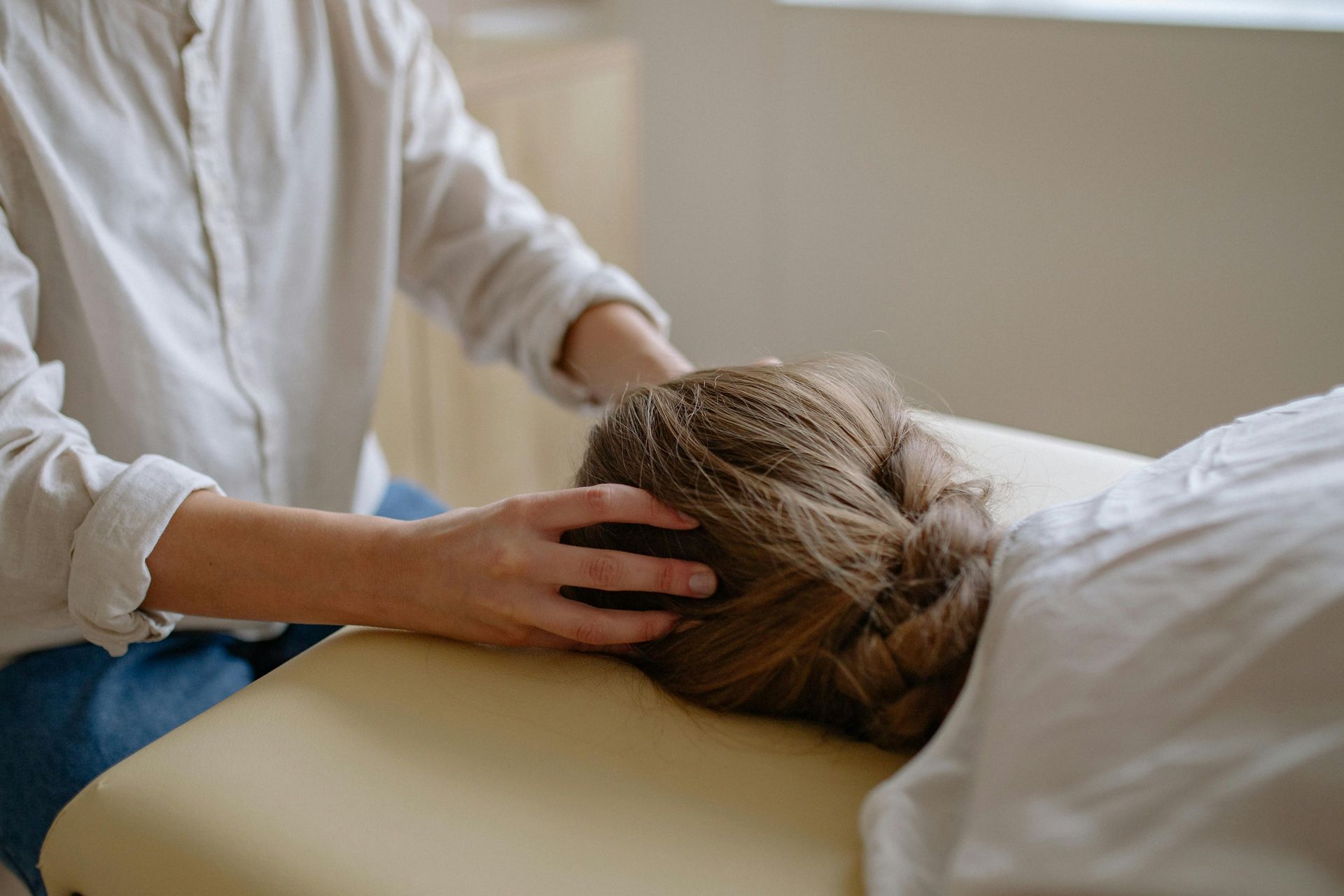 Person receiving a head massage on a treatment table in a calm, softly lit room