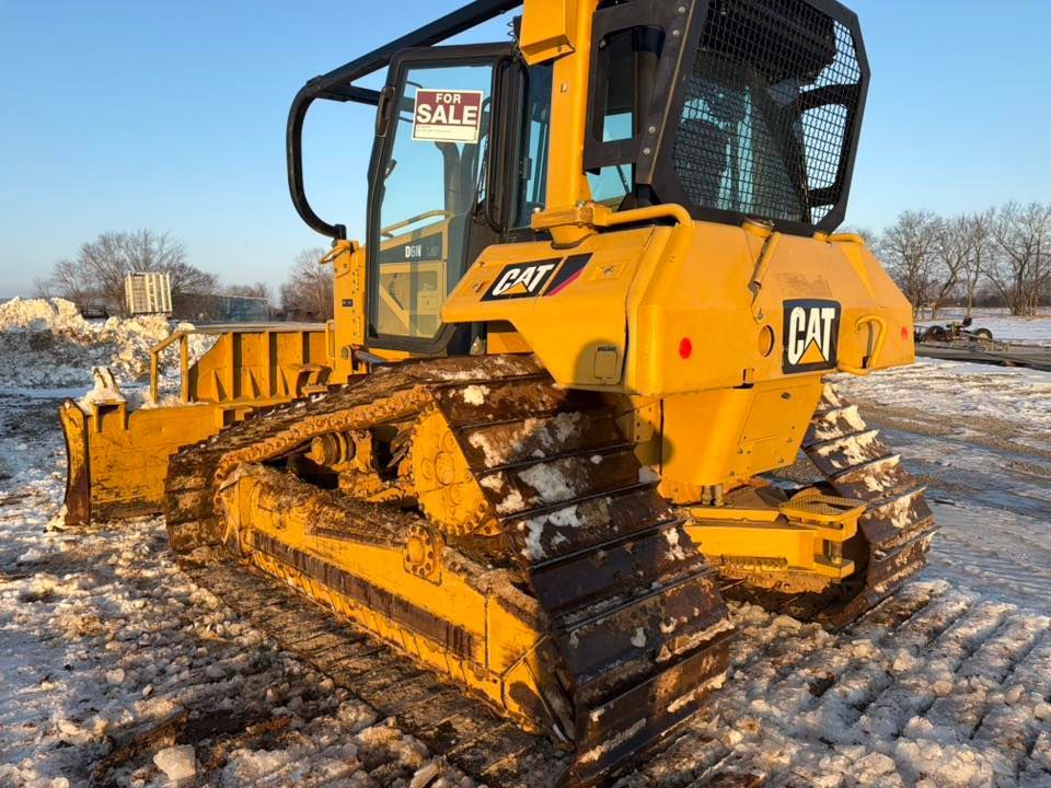 Yellow CAT bulldozer on a snowy construction site, with metal tracks and a black cab.