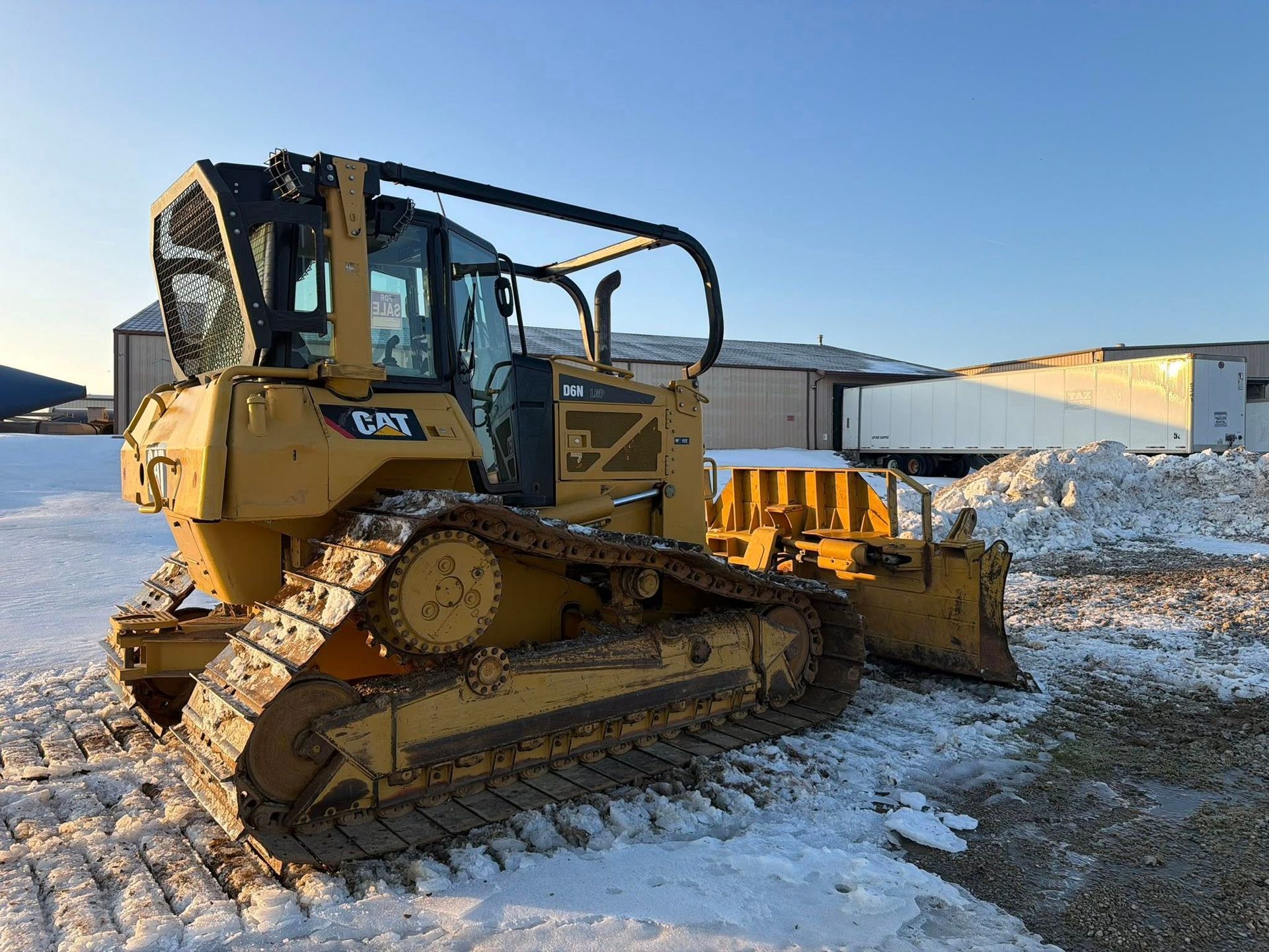Yellow bulldozer on a snowy construction site under a clear blue sky