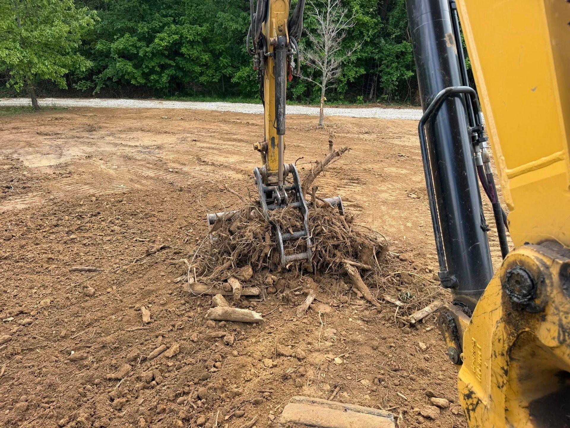 Excavator digging muddy earth on a construction site with trees in the background