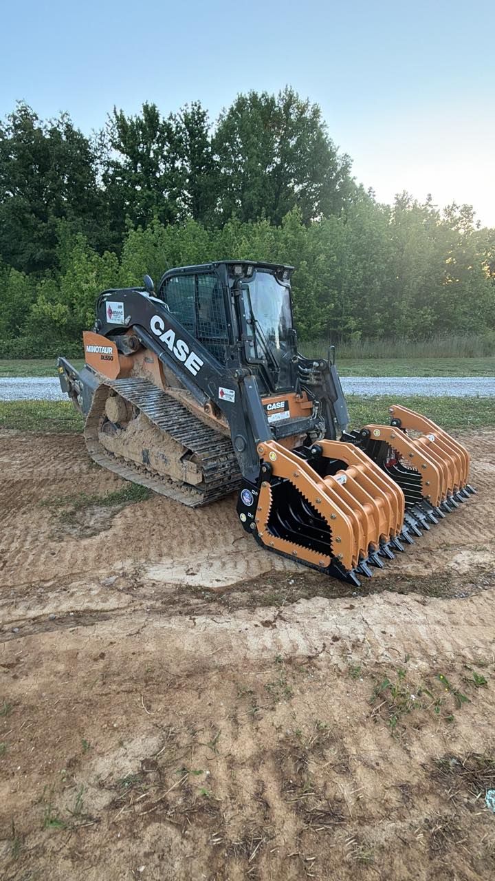Black CASE compact track loader with orange bucket attachments parked on dirt near trees at sunset