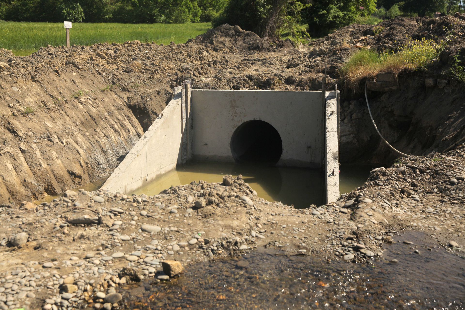 Concrete culvert drainage tunnel in an excavation site, surrounded by dirt and rubble