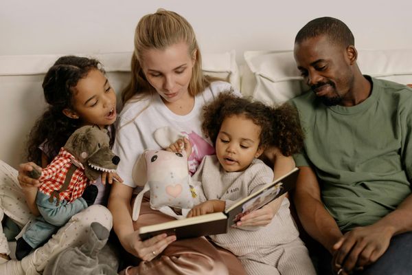 Foto vanFinch Logopediepraktijk, Een gezin leest samen een boek op de bank.