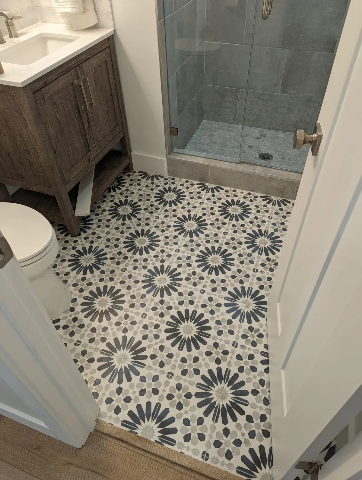 Bathroom with patterned floor tiles, vanity, toilet, and shower.