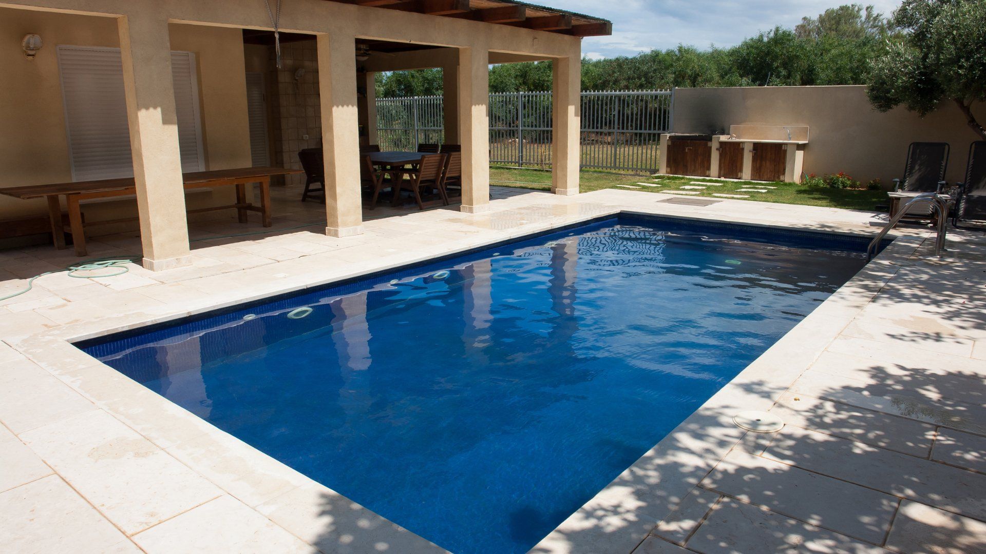 Smaller backyard pool off a house with a covered patio. The pool deck is newly constructed stamped concrete in Oshawa Ontario.