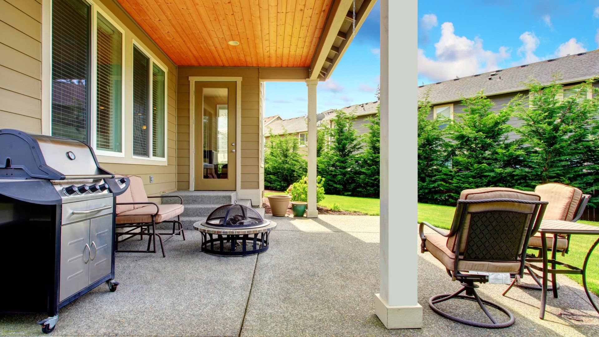 Small background concrete patio with some patio furniture, small firepit and a barbeque.