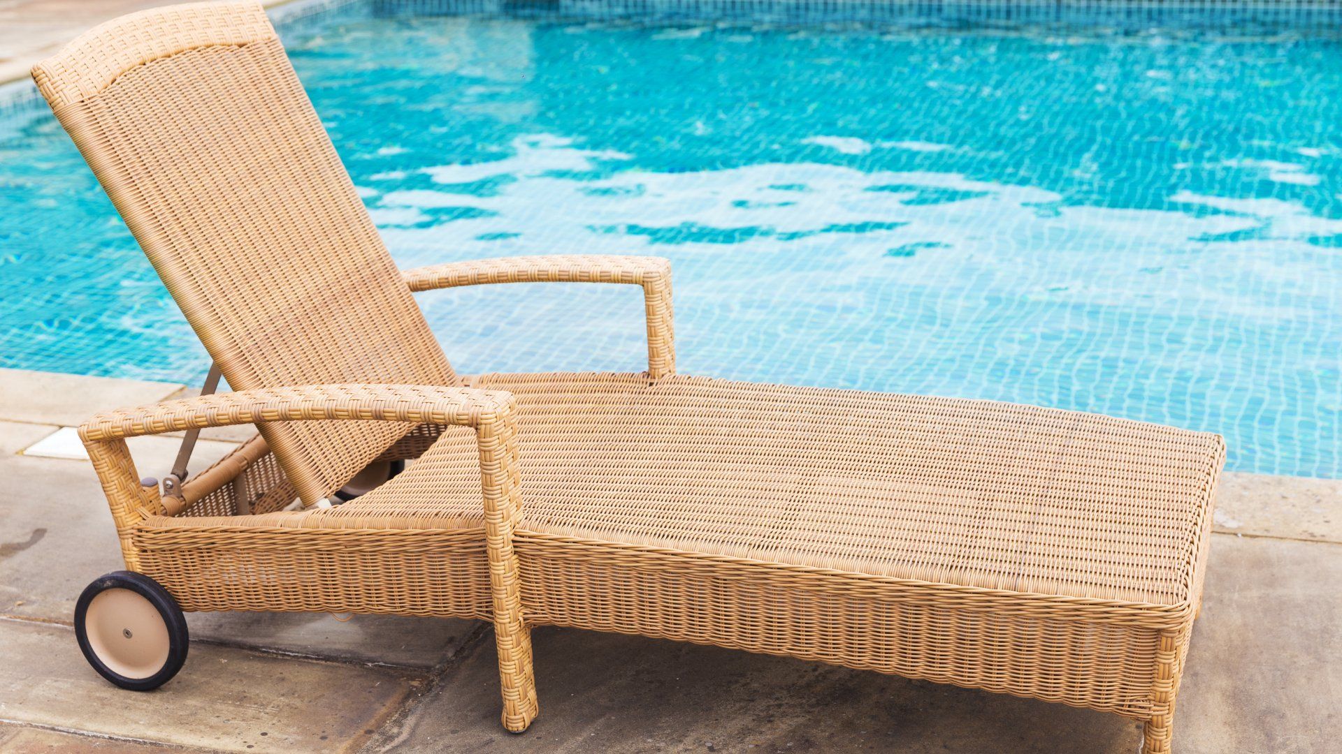 Closeup of a lounge chair on a concrete pool deck.