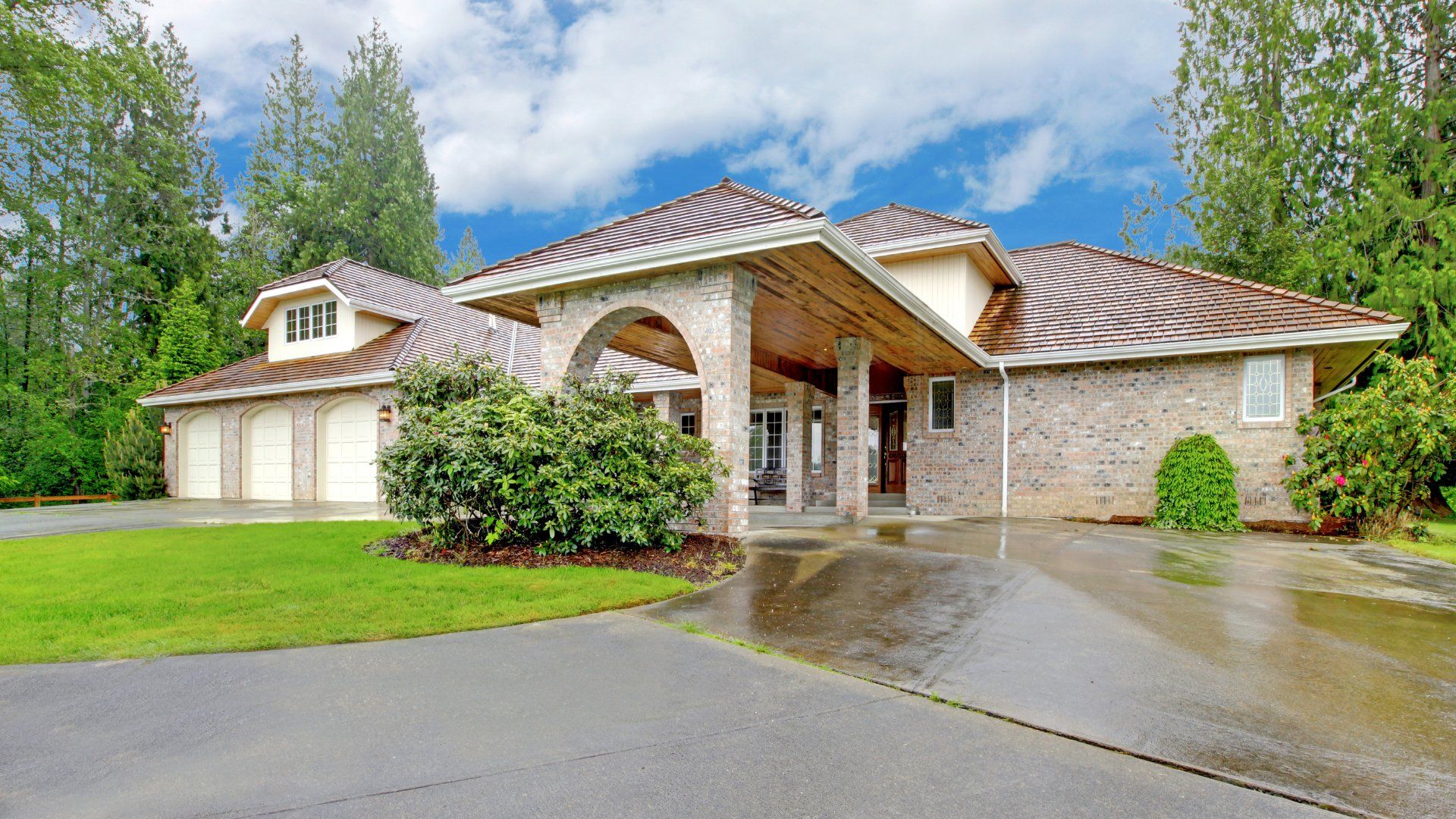 A curved concrete driveway in front of a house in Oshawa. The house features an overhang over the front door and a triple car garage.