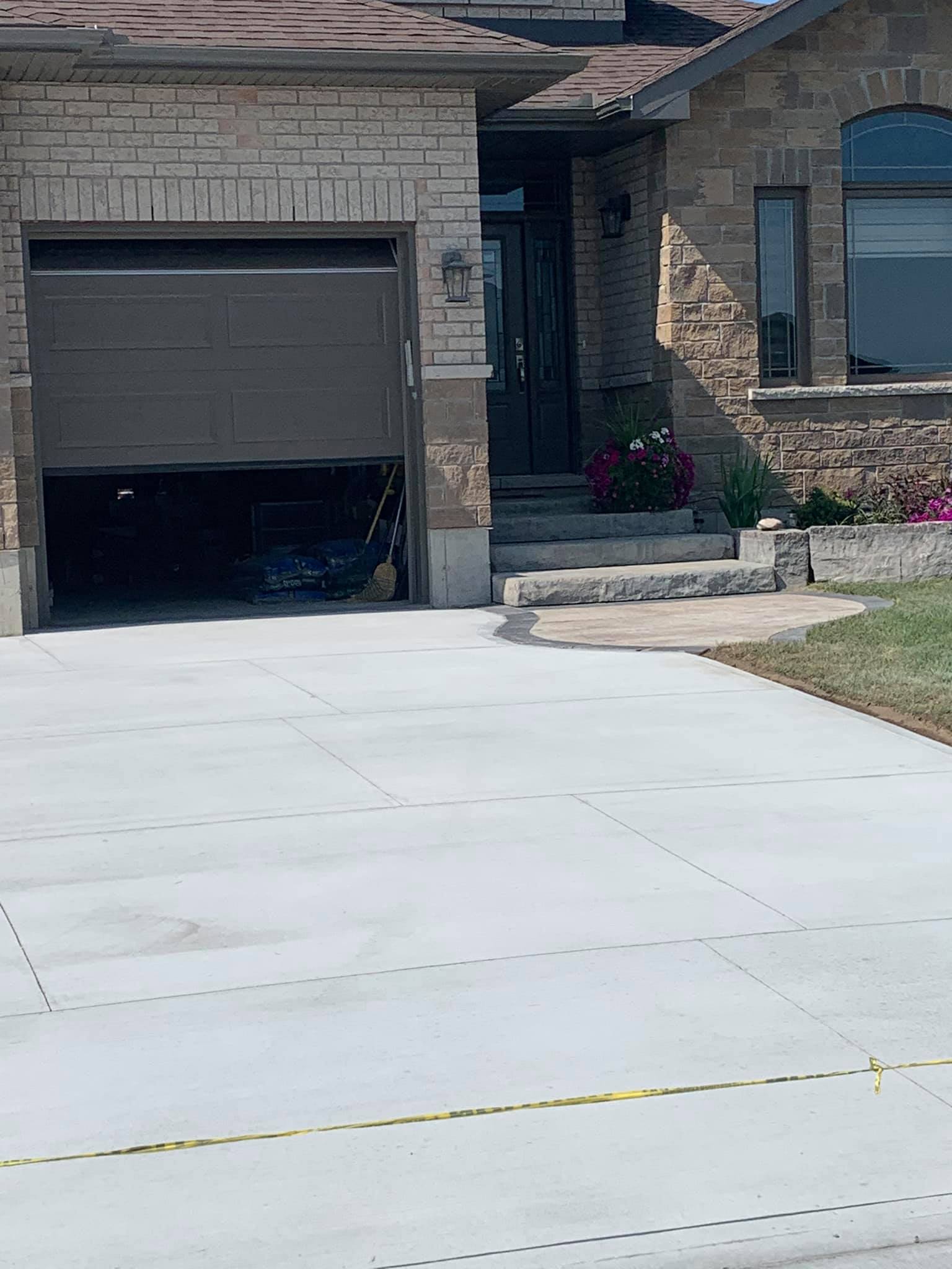 Concrete stamps on a new concrete driveway in Oshawa. The driveway leads up to a modern looking house with concrete steps leading up to the front door.