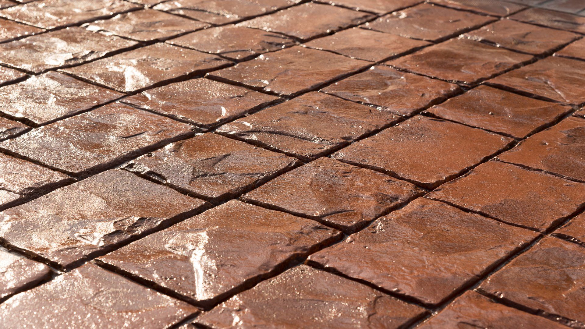 Closeup picture of a brown stamped concrete patio. The concrete has a patio stone design.