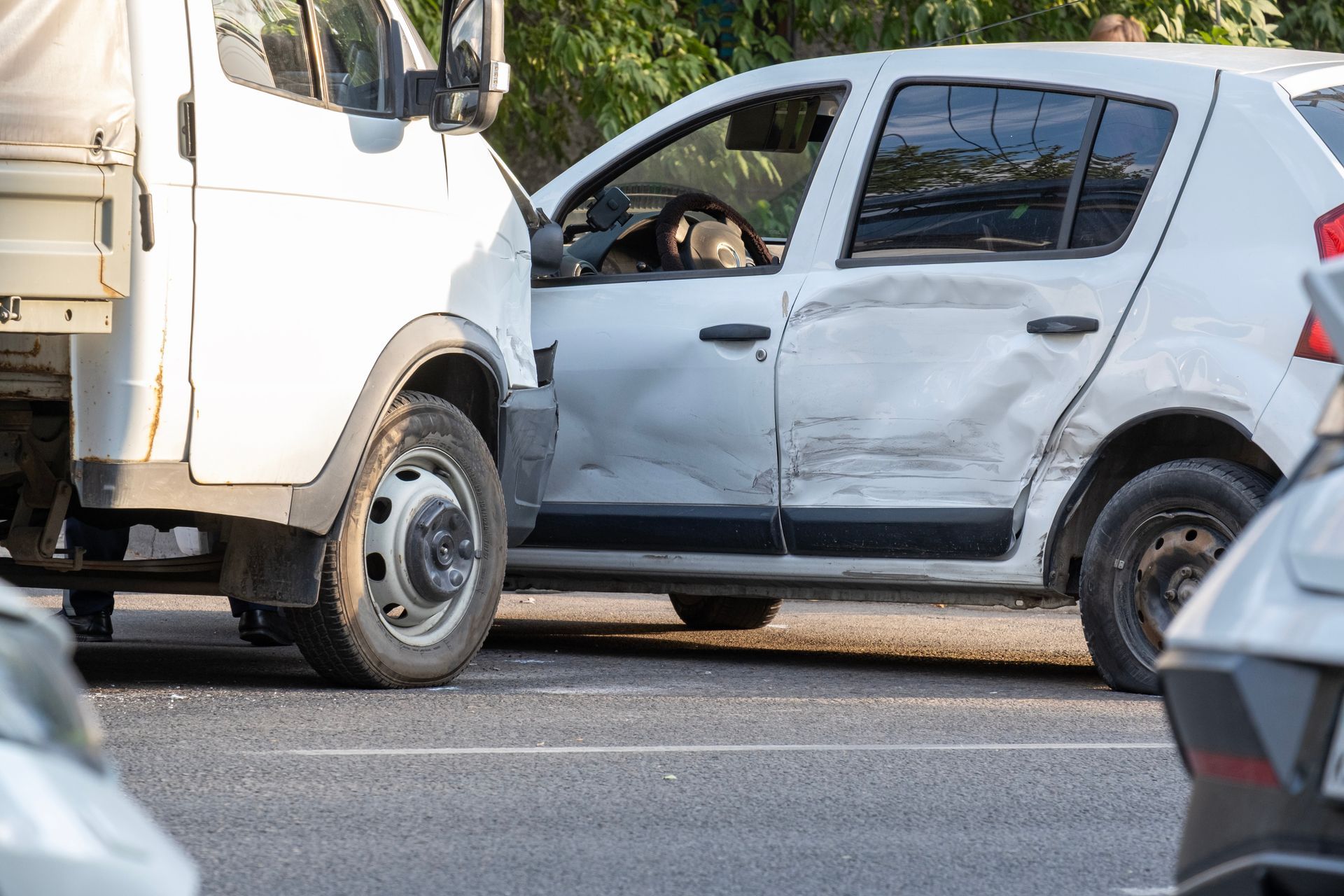 White SUV with a crushed side door after a collision with a truck on a road