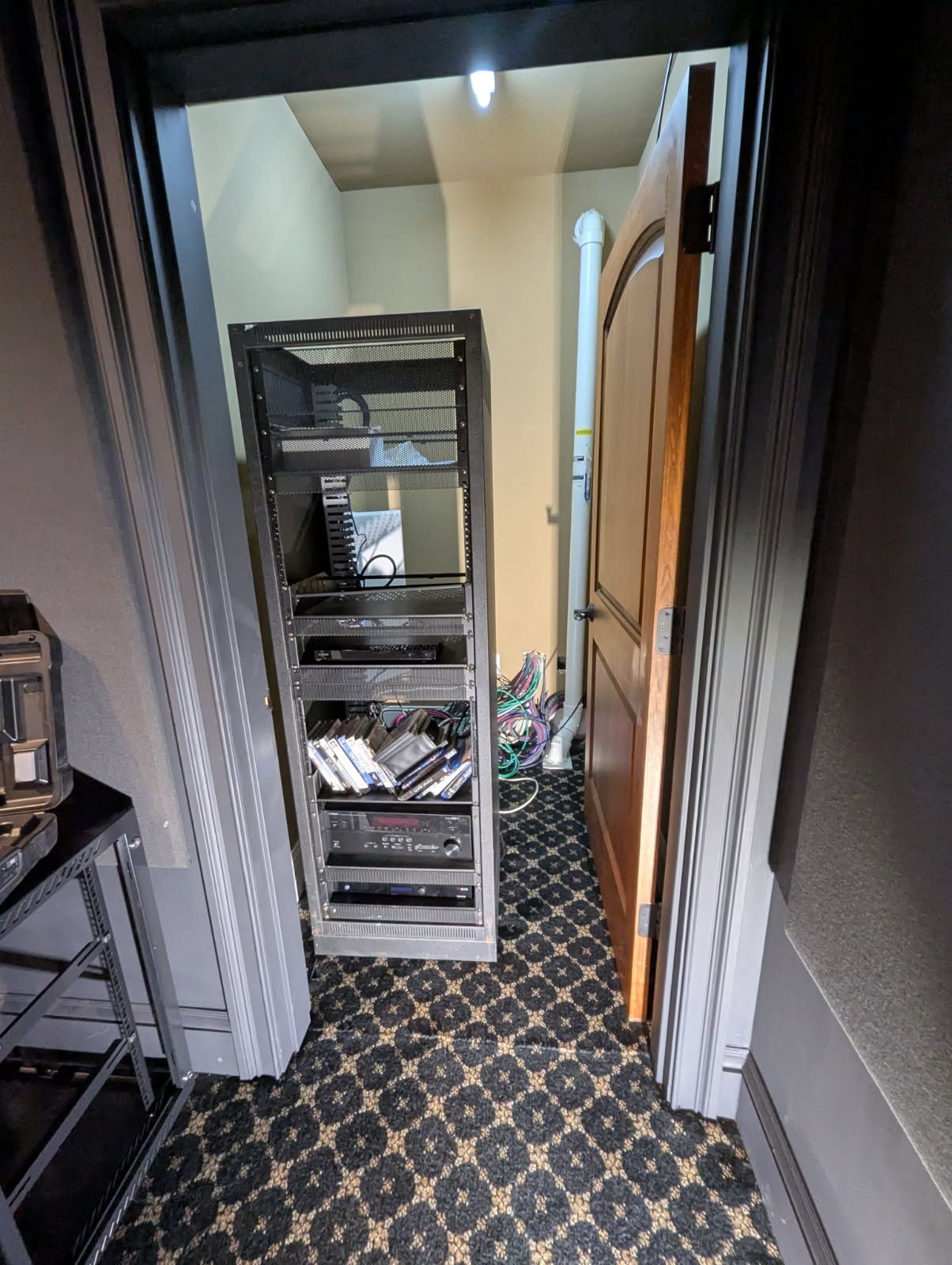 A hallway with a carpeted floor and a shelf in the middle of it.