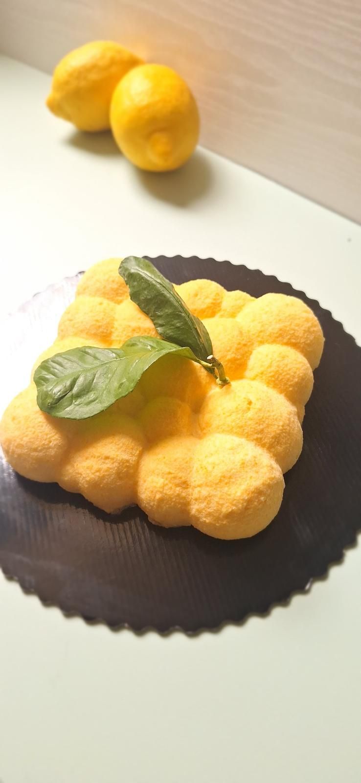 Agrumi di colore giallo brillante a forma di fiore su un piatto nero, con foglie verdi in cima.