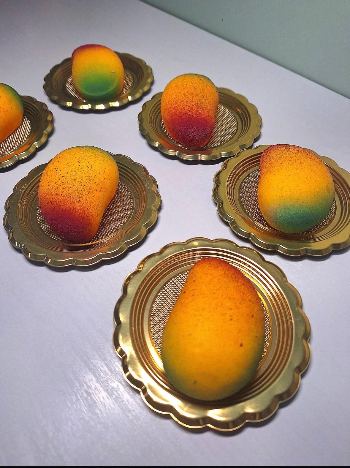 Mango su piatti color oro disposti su una superficie chiara