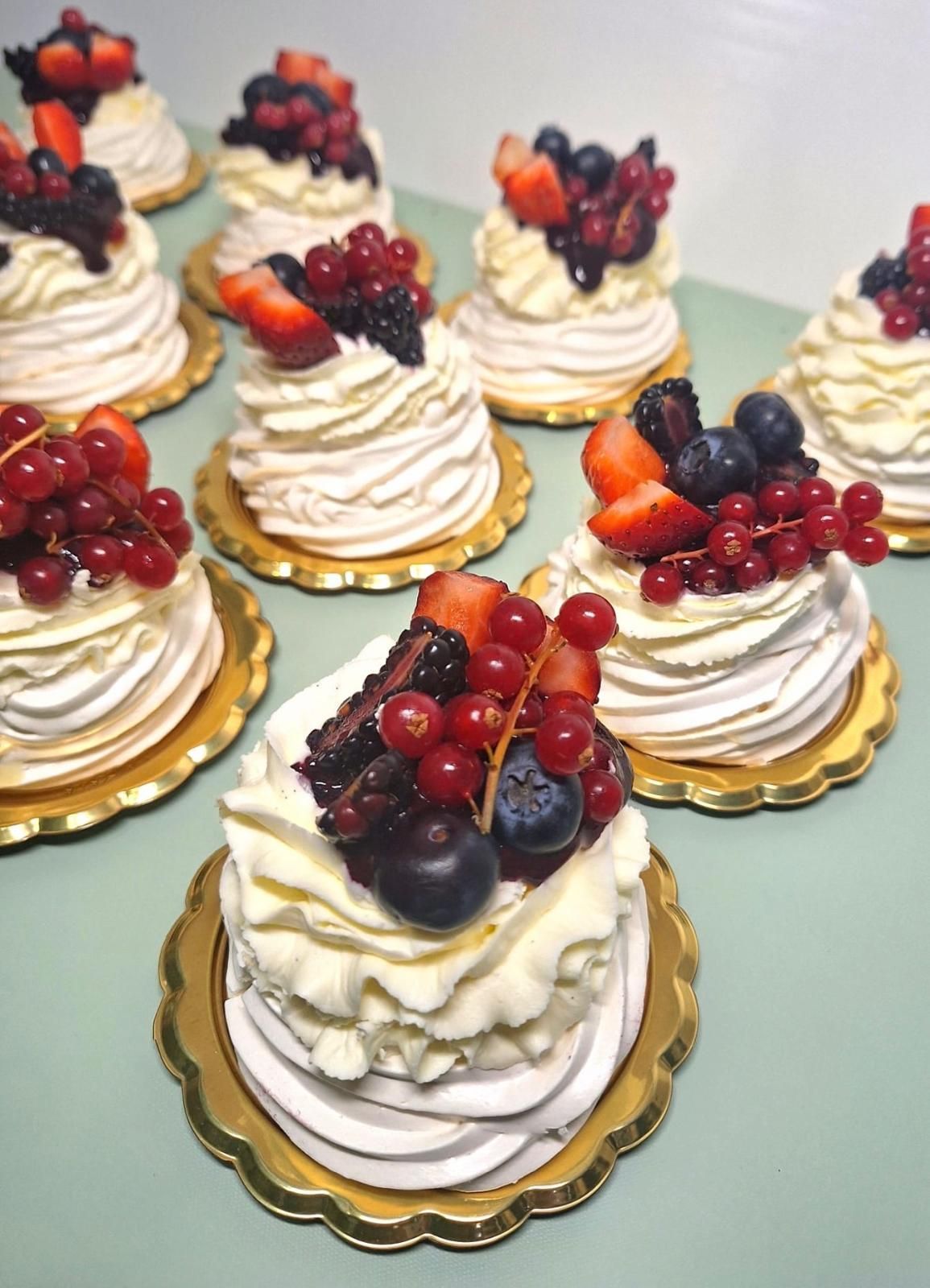 Piccoli pasticcini alla crema con frutti di bosco disposti su un tavolo