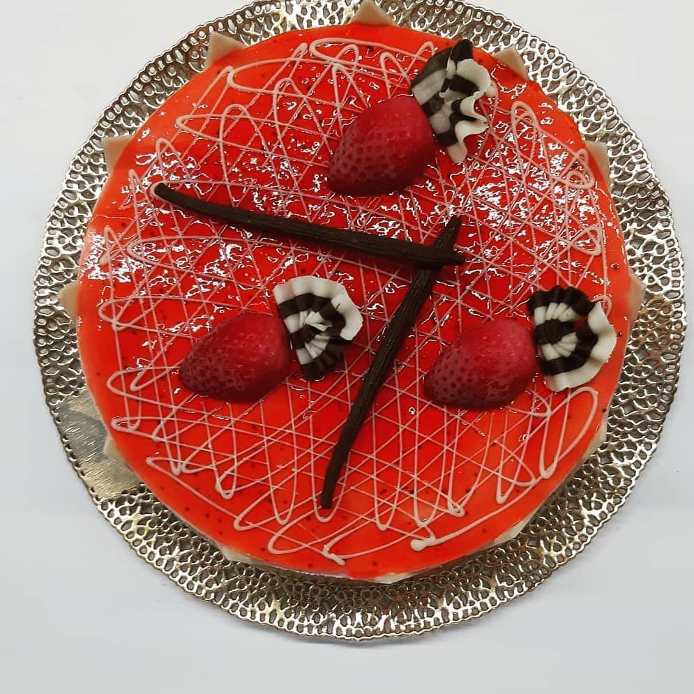 Torta rossa da dessert con fragole, decorazioni al cioccolato e glassa bianca su un piatto d'argento