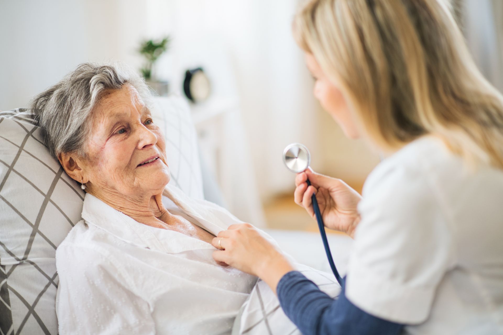 A nurse assesses an elderly woman's heart, highlighting the importance of home health care service. A nurse assesses an elderly woman's heart, highlighting the importance of home health care service.