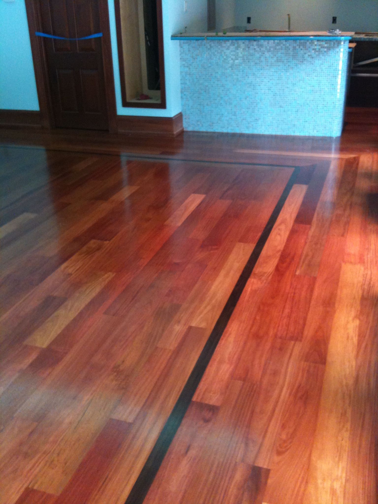 Polished hardwood floor in an empty room with blue walls and a doorway.